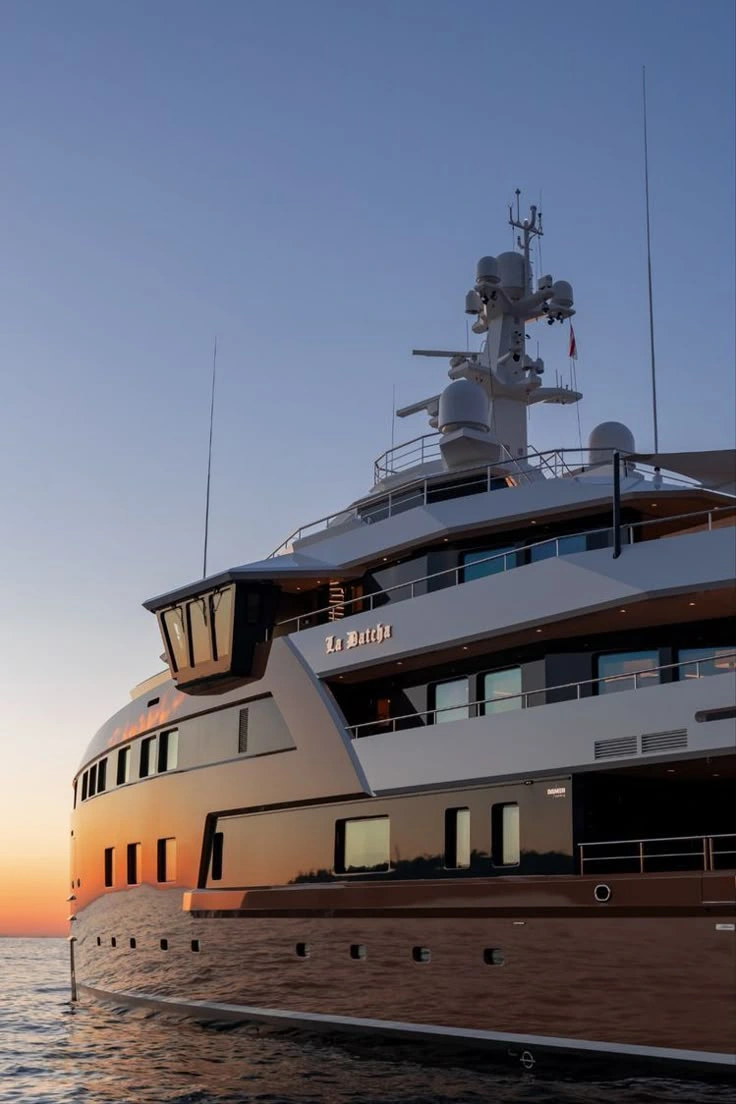 Superyacht hull and waterline at dusk with sunset reflections on calm water