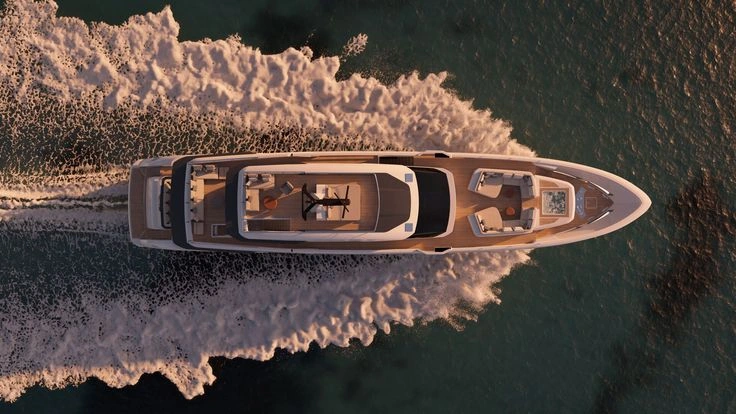 Aerial view of a superyacht underway, leaving a wake on open water