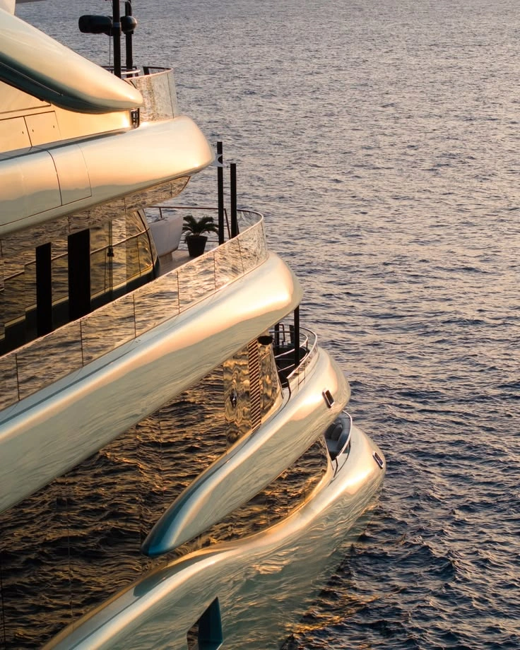 Superyacht deck terrace with lounge seating above calm water at golden hour