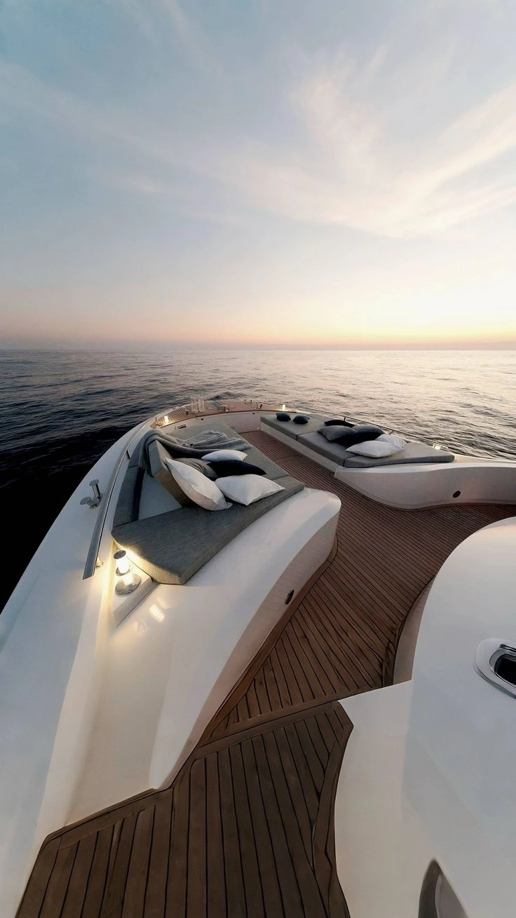 Superyacht bow lounge with teak deck facing a sunset horizon